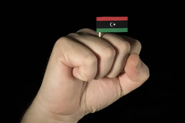 Człowiek pięść rękę z libijskiego flagi na białym na czarnym tle — Zdjęcie stockowe