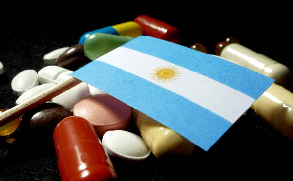 Bandera argentina con muchas píldoras médicas aisladas en negro —  Fotos de Stock