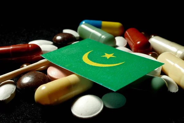 Bandeira mauritana com muitos comprimidos médicos isolados em preto — Fotografia de Stock