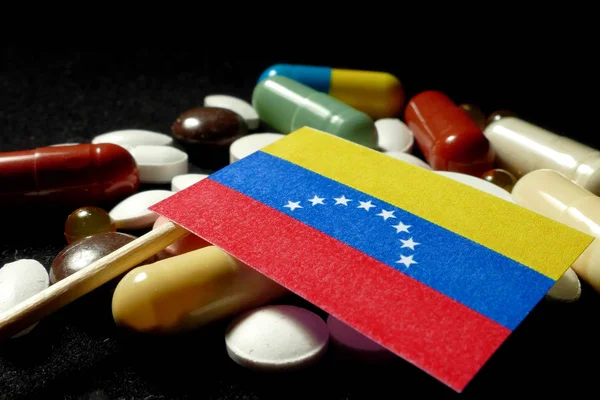 Bandiera venezuelana con un sacco di pillole mediche isolate su nero — Foto Stock