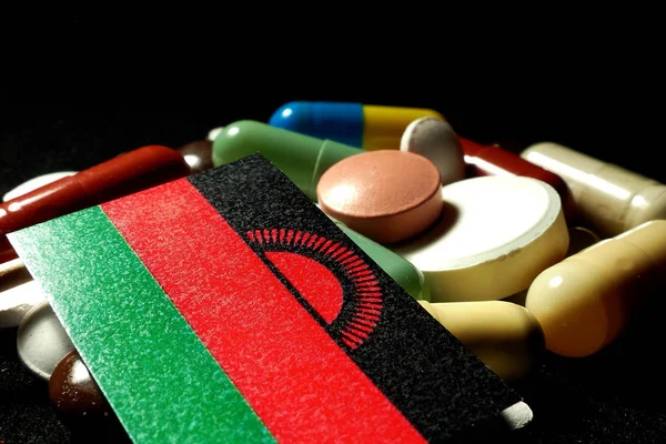 Bandeira do Malawi com muitos comprimidos médicos isolados em preto — Fotografia de Stock