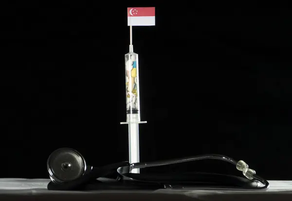 Steteskop ve Singapurlu bayrağı siyah bir arka plan üzerinde enjekte ederek uyuşturucu dolu şırınga — Stok fotoğraf