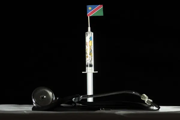 Namibya bayrağı siyah bir arka plan üzerinde enjekte ederek uyuşturucu stetoskop ve şırınga dolu — Stok fotoğraf