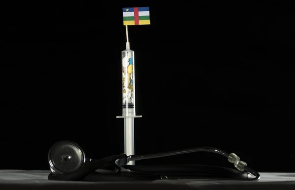 Orta Afrika Cumhuriyeti bayrağı siyah bir arka plan üzerinde enjekte ederek uyuşturucu stetoskop ve şırınga dolu — Stok fotoğraf