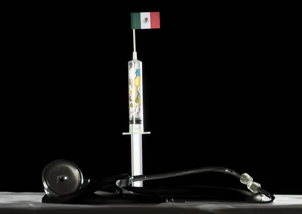 Стетоскоп и шприц, наполненные наркотиками, вводящими мексиканский флаг на черном фоне — стоковое фото
