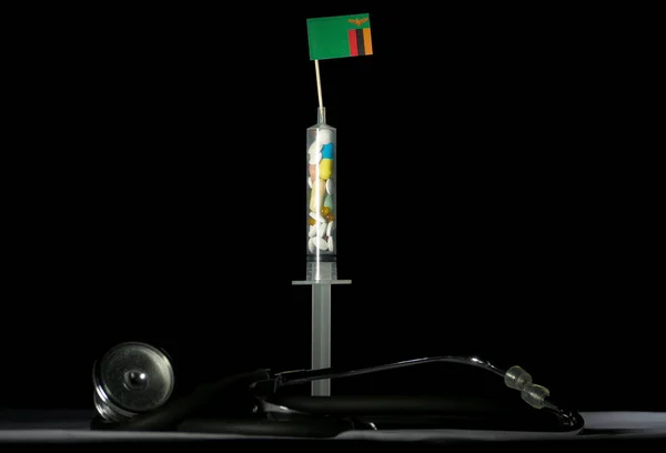 Estetoscopio y jeringa llenos de drogas que inyectan la bandera de Zambia sobre un fondo negro —  Fotos de Stock
