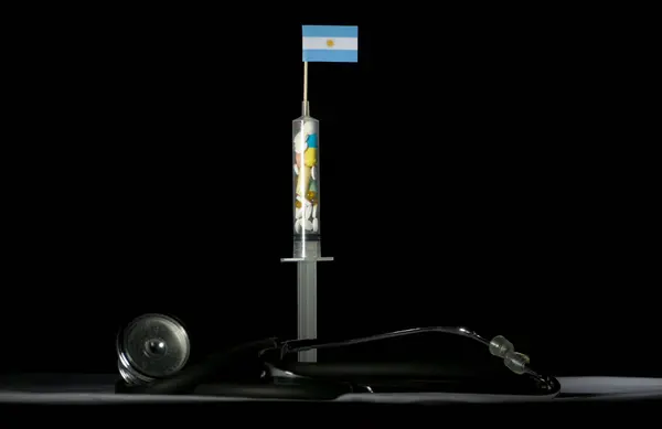 Стетоскоп и шприц, наполненные наркотиками, вводящими аргентинский флаг на черном фоне — стоковое фото