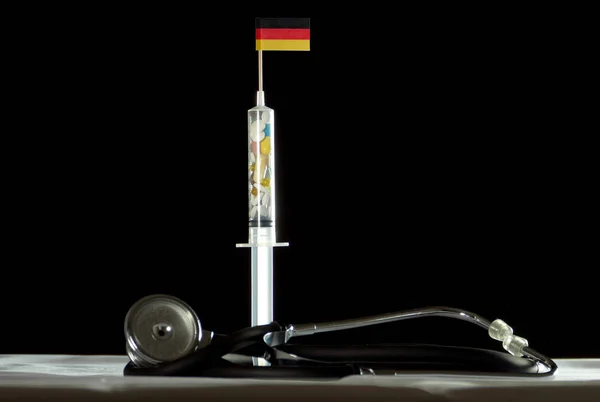 听诊器、 注射器装满药物注射在黑色背景上的德国标志 — 图库照片