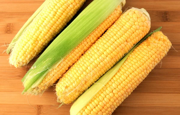 Corn cob on wooden plank isolated on white — Stock Photo, Image