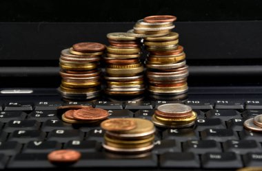 Beyaz arka plan üzerinde izole bir dizüstü bilgisayar üzerinde paralar