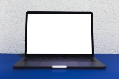 Modern dizüstü bilgisayarın boş maketi, hayalet mavi masa, beyaz desenli duvar arkaplanı.