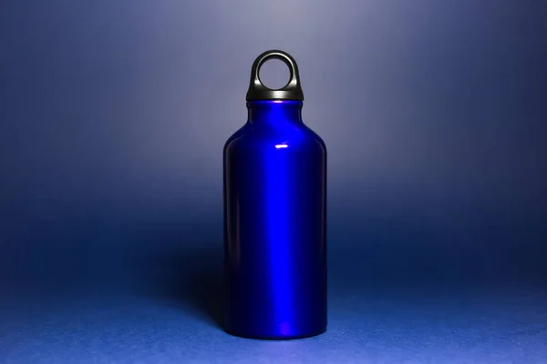 Close-up of reusable, aluminium thermo eco water bottle phantom blue of color, isolated on dar blue background.