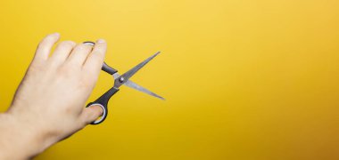 Sarı arka planda erkek el makasının yakın çekimi..