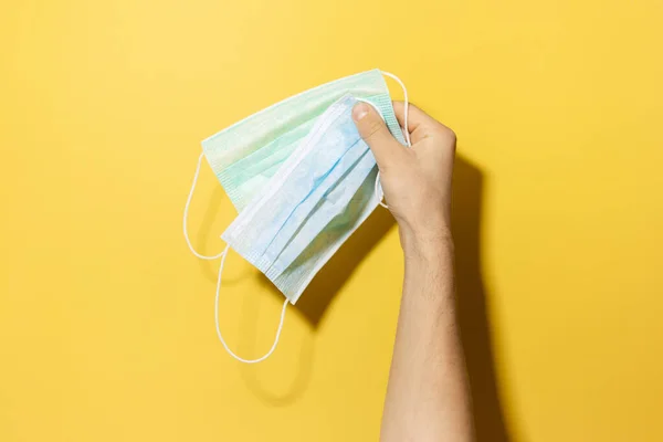 Close Mão Masculina Segurando Máscaras Médicas Fundo Amarelo — Fotografia de Stock