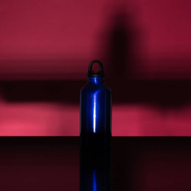Pembe mercan zemin üzerinde izole edilmiş alüminyum termo eko su şişesinin klasik mavisi..