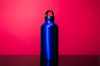 Pembe mercan zemin üzerinde izole edilmiş alüminyum termo eko su şişesinin klasik mavisi..
