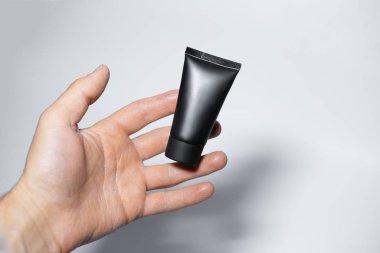 Siyah krem tüplü, beyaz arka planda izole edilmiş erkek eli..