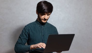 Genç bir adamın portresi, dizüstü bilgisayar, klavyede daktilo, ekrana bakmak..