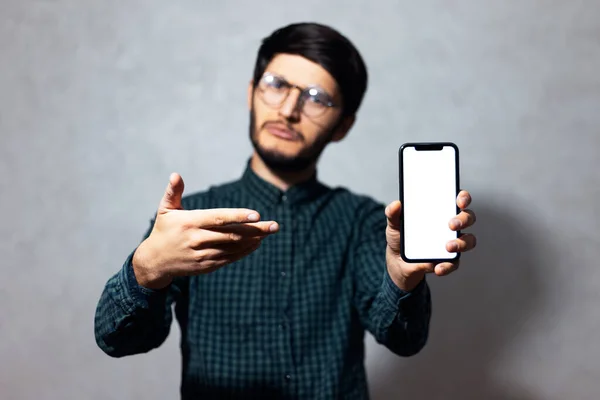 Retrato Jovem Vestindo Óculos Camisa Verde Mostrando Com Dedo Smartphone — Fotografia de Stock