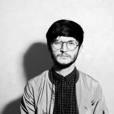 Yuvarlak gözlüklü genç adamın siyah beyaz portresi.