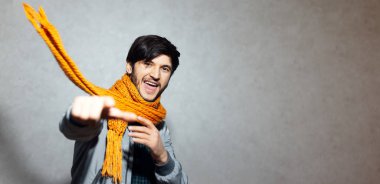 Kamerayı işaret eden mutlu adamın portresi, gri bombacıyla turuncu eşarp takıyor..