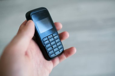 Eski siyah cep telefonunu tutan adamın yakın çekimi..