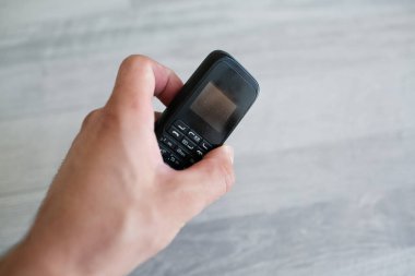 Eski siyah cep telefonunu tutan adamın yakın çekimi..