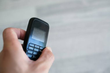 Eski siyah cep telefonunu tutan adamın yakın çekimi..