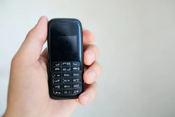 Close-up of man hand holding old black mobile phone.