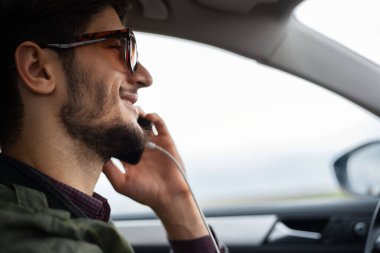 Akıllı telefondan konuşan sürücünün yüzünün yakın çekimi.