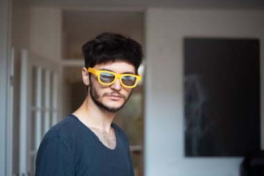 Sarı güneş gözlüklü, ciddi bir gencin portresi..