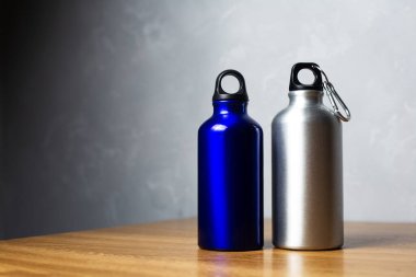 Gümüş ve parlak mavi termo şişe ahşap masada..