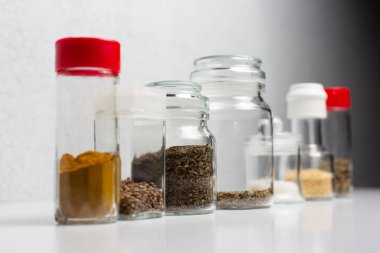 Beyaz arka planda, cam bardaklarda farklı baharatlar. 