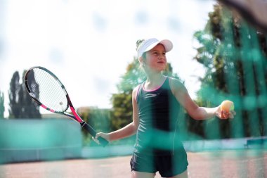 Spor sahasında tenis oynayan genç kızın portresi.