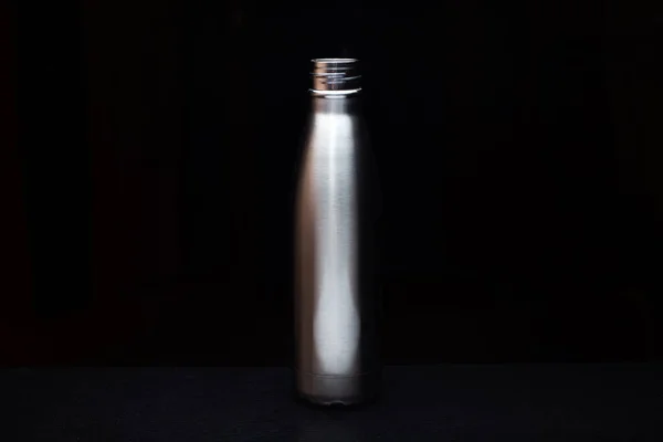 Close-up of steel thermo bottle on black.