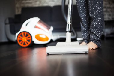 Genç kız koyu laminat için elektrikli süpürge kullanıyor..