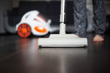 Genç kız koyu laminat için elektrikli süpürge kullanıyor..