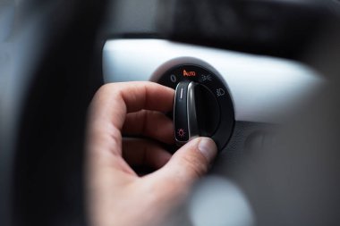 Erkek elinin yakın çekimi, arabadaki ışık düğmesini aç.