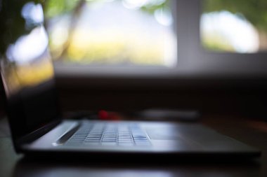 Pencerenin arka planında modern dizüstü bilgisayarın yakın plan görüntüsü.