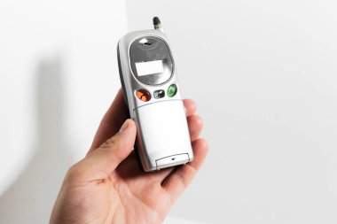 Beyaz arka planda izole edilmiş eski cep telefonunu tutan bir erkek..