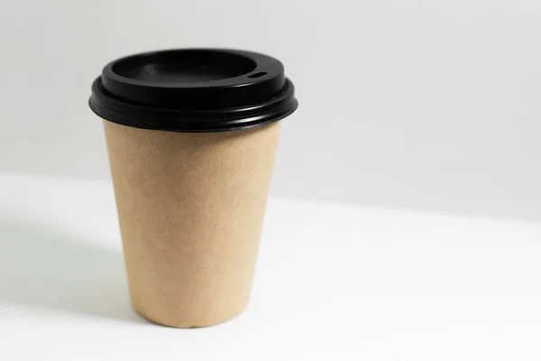 コーヒー用の使い捨てペーパーカップのクローズアップは 白い背景に隔離された黒い蓋付きです — ストック写真