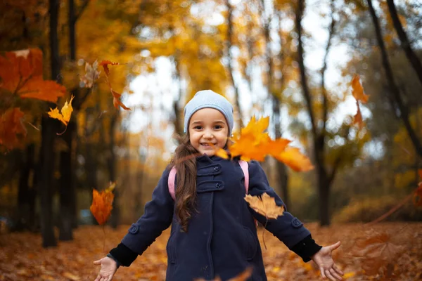Sarı ve turuncu kuru sonbahar yapraklarıyla oynayan neşeli çocukların portresi.