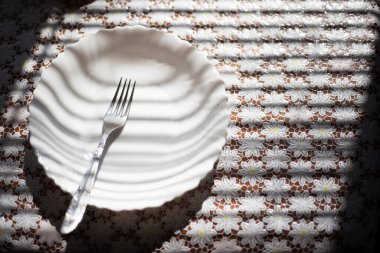 Masadaki çatalın beyaz tabakta yakın plan görüntüsü..