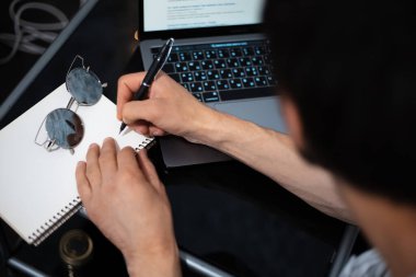 Dizüstü bilgisayardan erkek el yazısının defter bilgisine yakın plan.