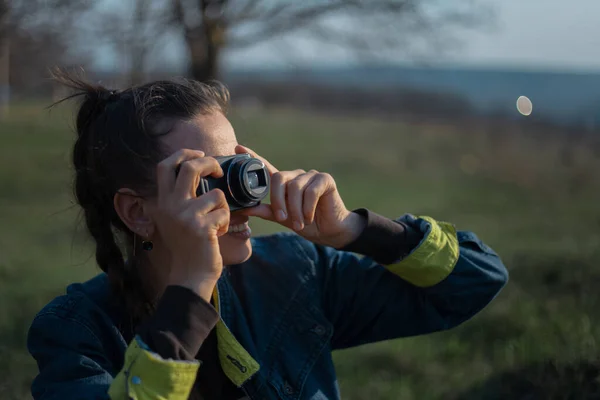 日没を背景にデジタル写真カメラを持つ少女の肖像 — ストック写真