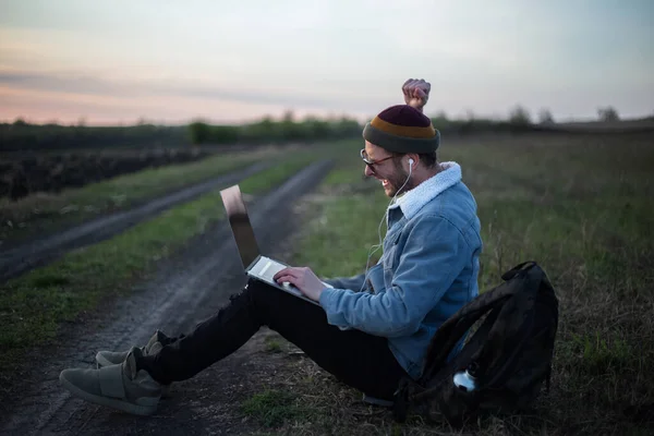 Millennial Hipster Man Arbetar Laptop Med Hörlurar Fält Vid Solnedgången — Stockfoto