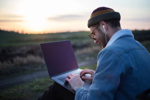 Millennial Hipster Man Working Laptop Earphones Field Sunset — Stock Photo, Image