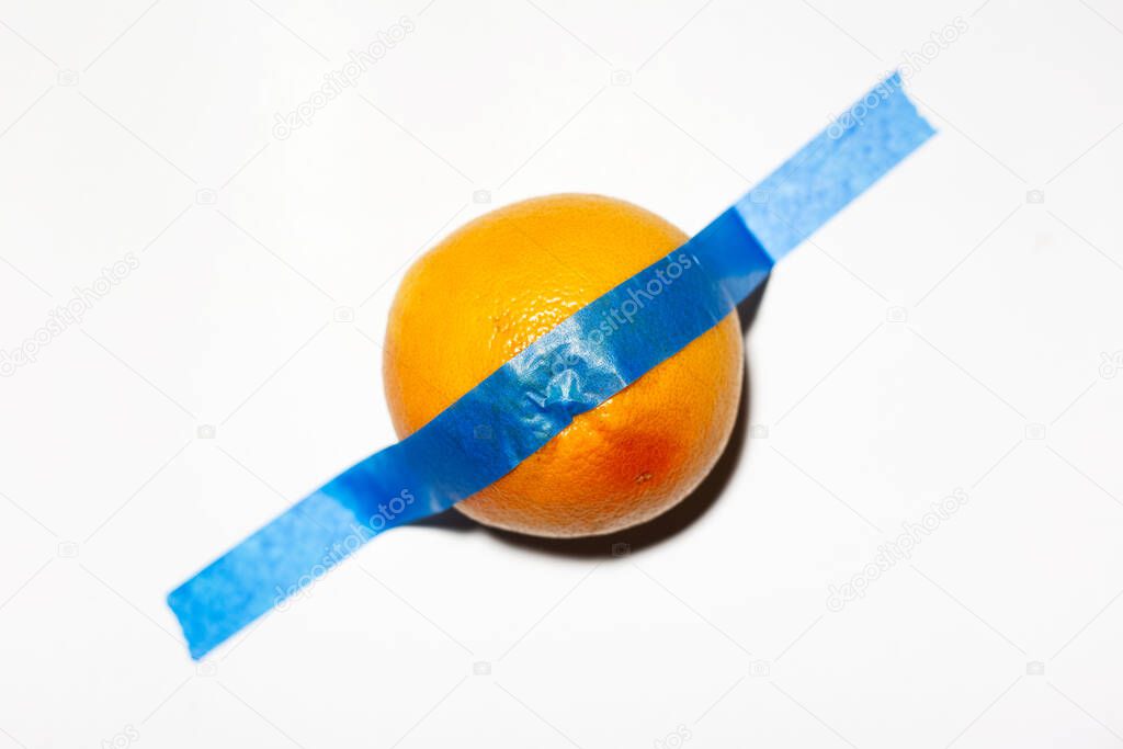 Close-up of grapefruit taped to the white wall.
