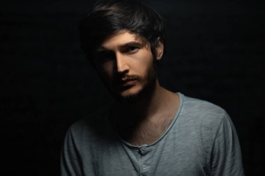 Siyah arka planda genç bir adamın dramatik koyu portresi.