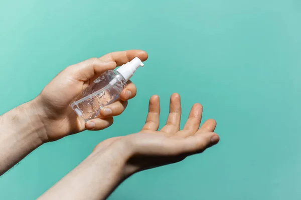 Aqua menthe renginin arka planına antiseptik jel süren erkek elleri yakın plan. Antibakteriyel sabun kullanan bir adam..